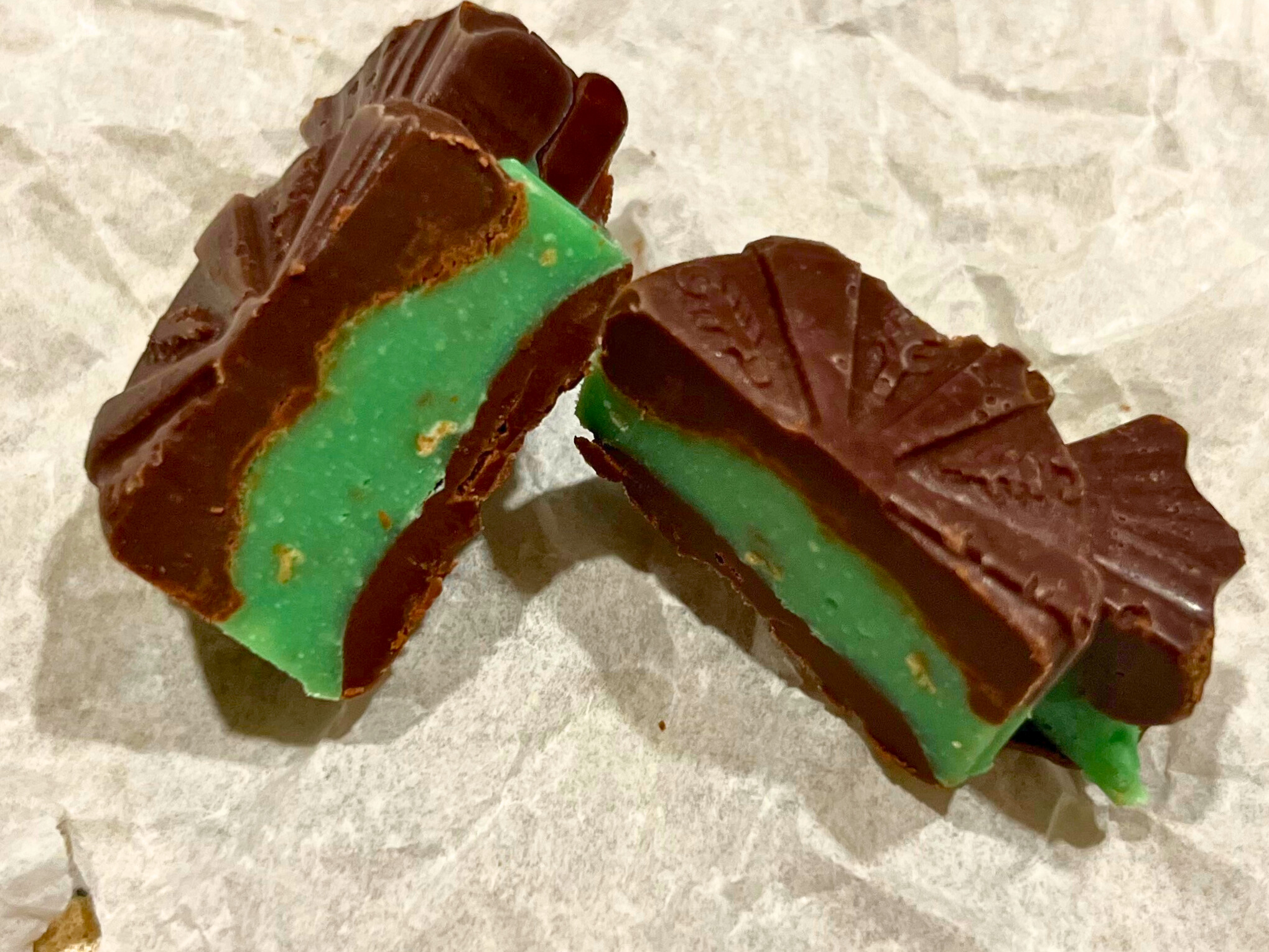 A chocolate mint candy cut in half on a piece of parchment paper.