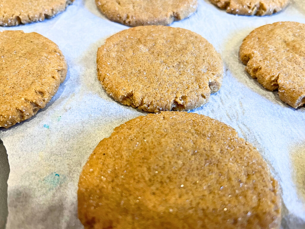 Baked and cooled gingerbread cookies on a baking sheet with parchment paper.