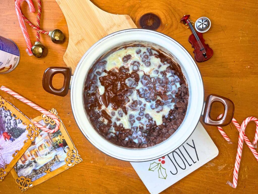 Melting chocolate chips and sweetened milk in a white sauce pot.