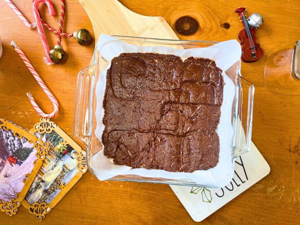 A square casserole dish with a chocolate base pressed inside.