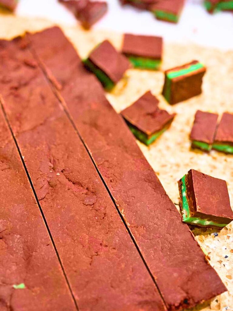 Layered chocolate and mint. The solid chocolate is being cut into little bite-sized squares.