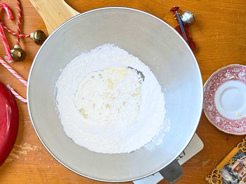 A metal bowl with butter and icing sugar inside.