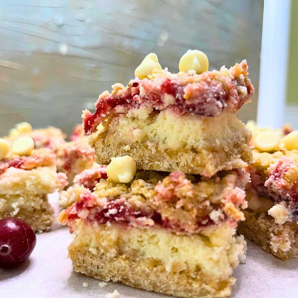 Two stacked cranberry cheesecake bars. There are more in the background.