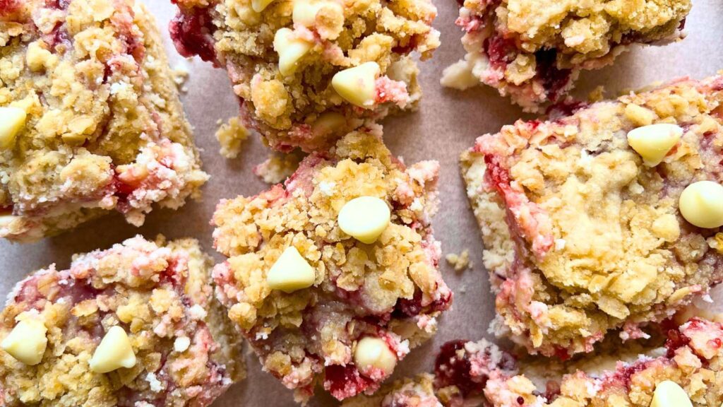 An arrangement of sliced cranberry cheesecake squares on a piece of parchment paper.