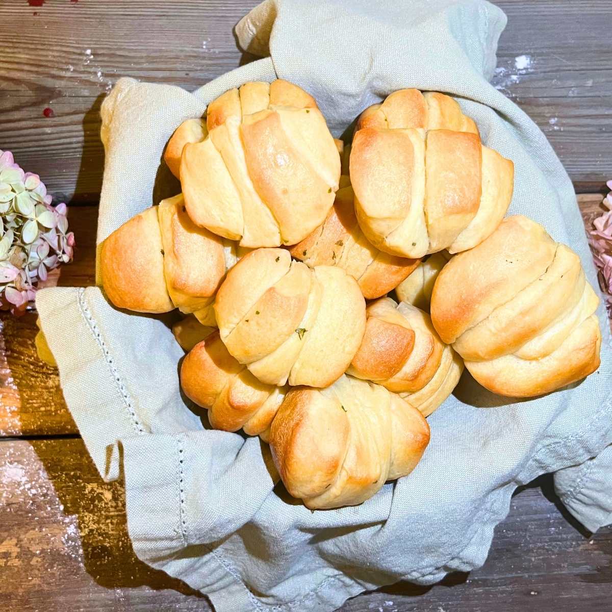 A basket of pull apart rolls on a wooden table.