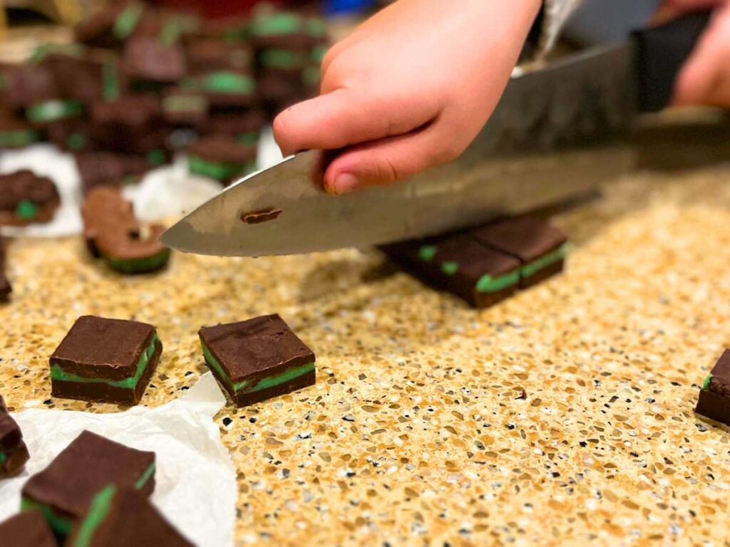 A child cutting mint chocolate into bite-sized squares.