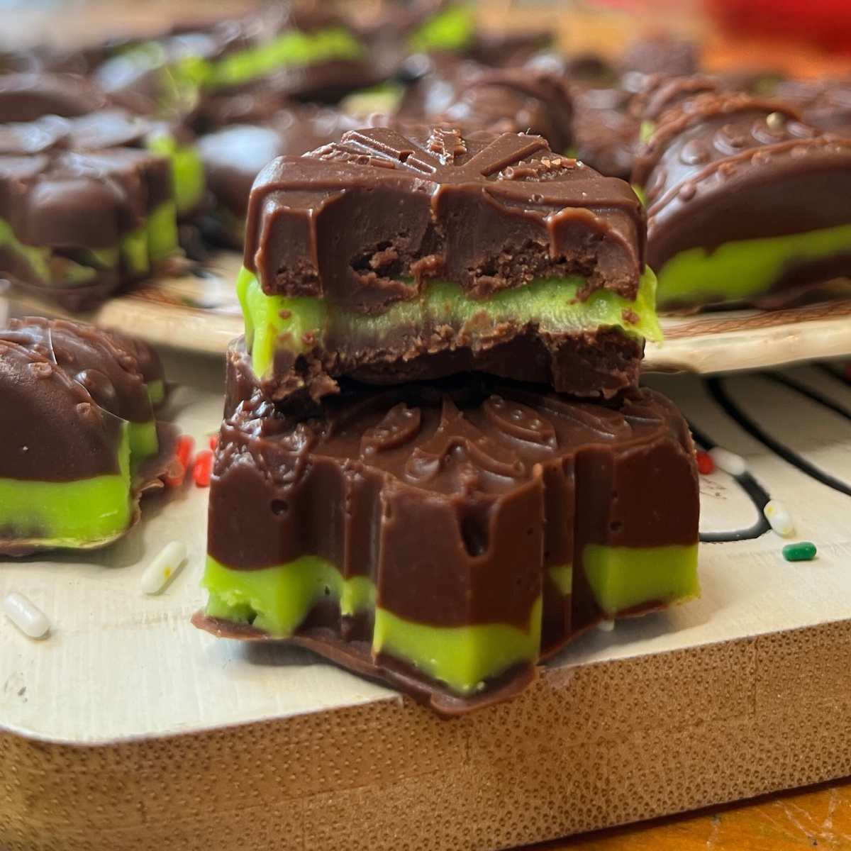 Mint chocolate candies on a cutting board. One has a bit out of it.