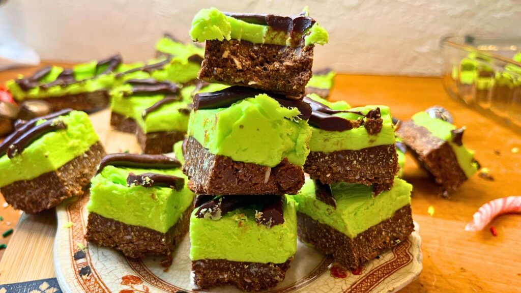 A stack of mint chocolate squares on a brown floral plate. The top one has a bite out of it.