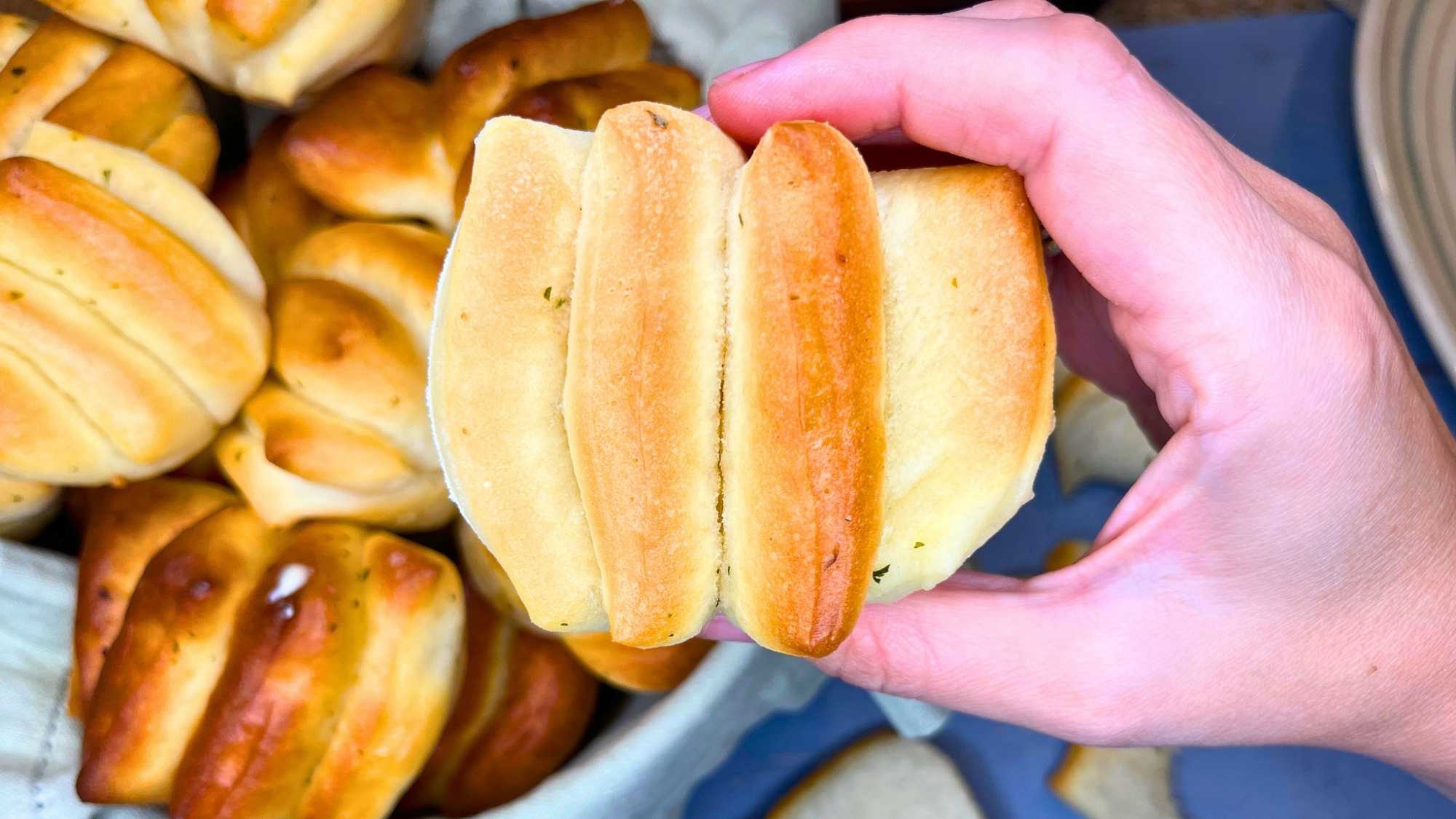 There is a woman holding a pull apart dinner roll.