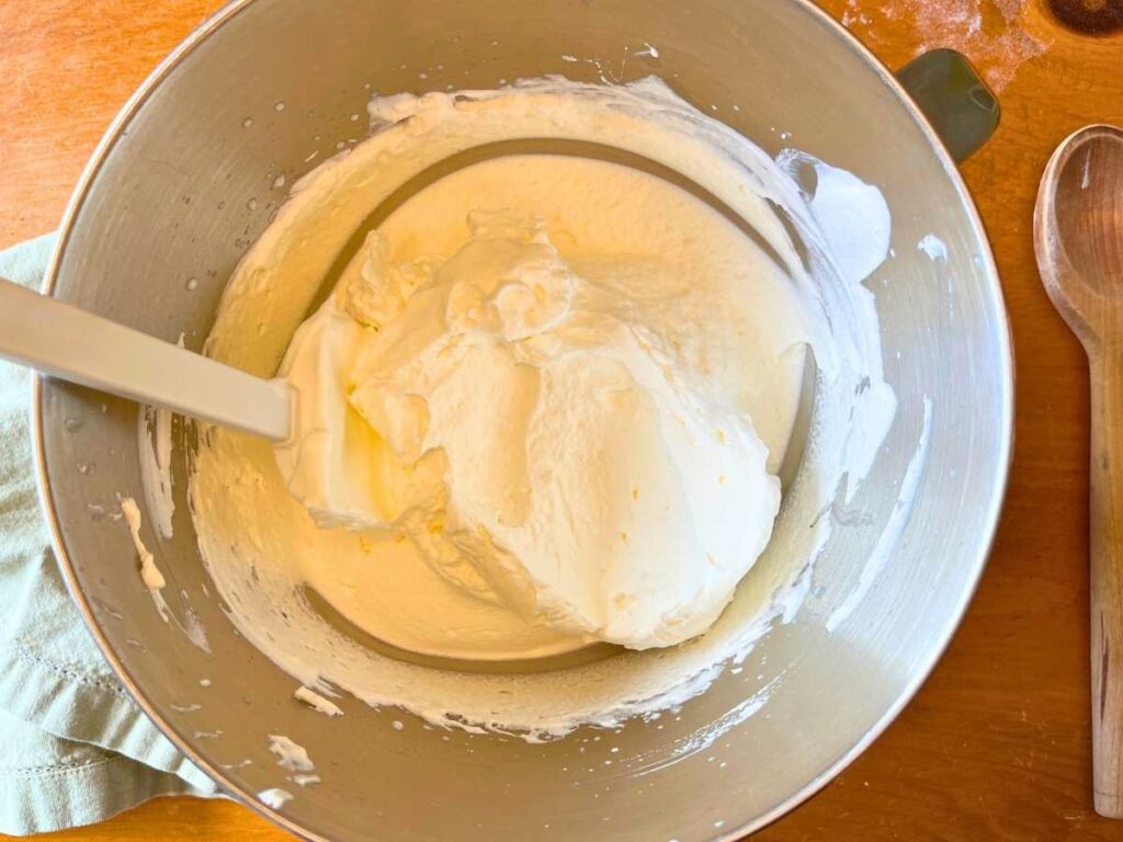 A metal bowl with batter and whipped egg whites on top.