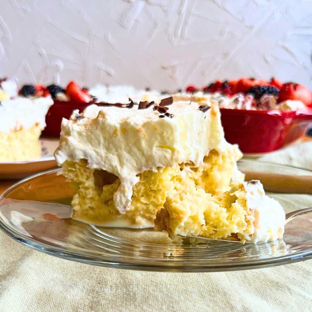 A slice of tres leches cake on a glass plate.