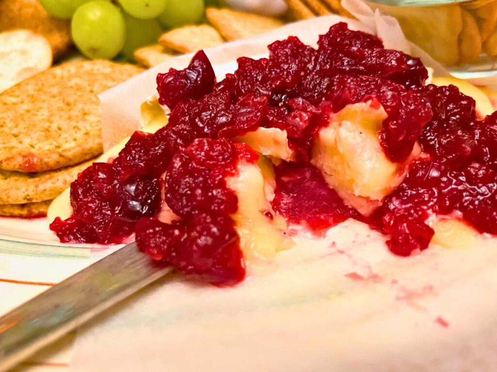 A side view of a baked Brie with leftover cranberry sauce.