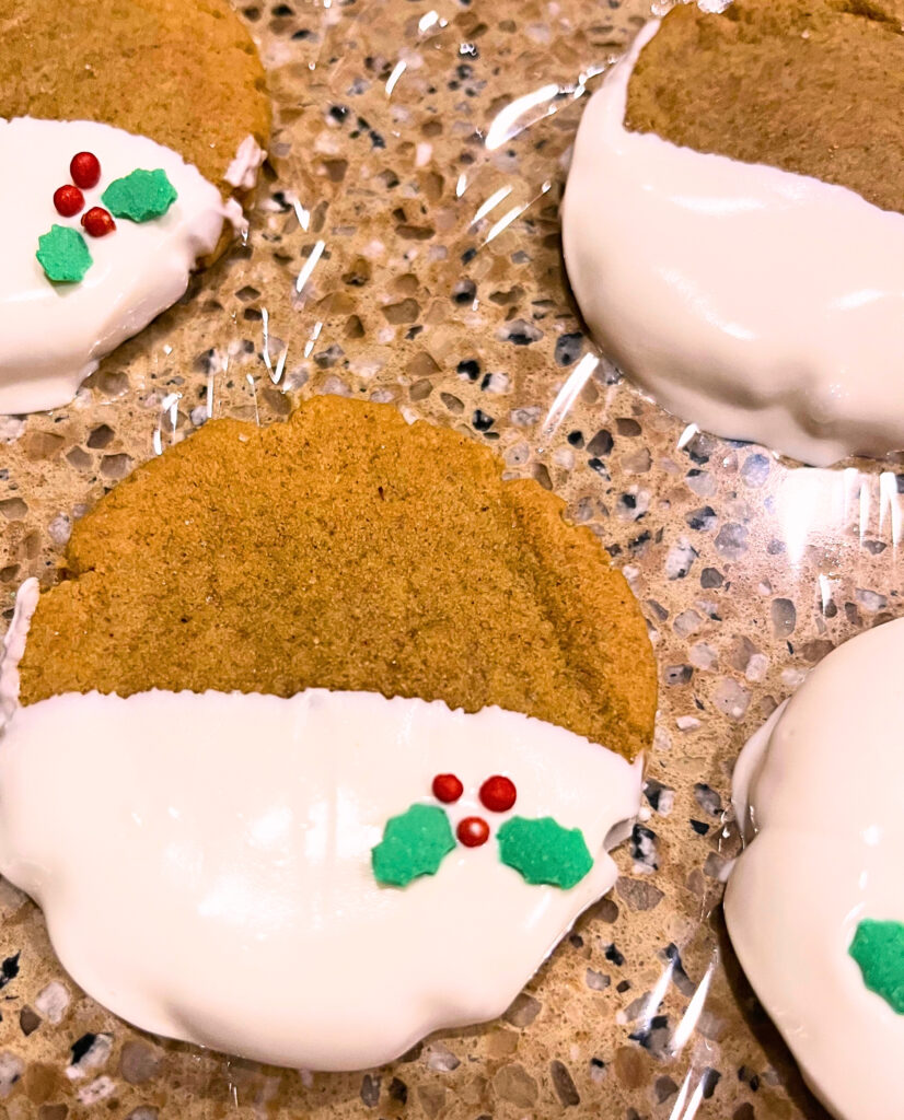 Gingerbread cookies on a counter top with white chocolate and Christmas sprinkle decorations.