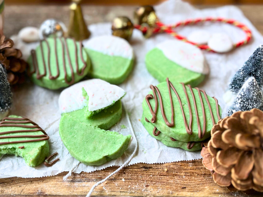 An array of mint Christmas cookies on a piece of parchment paper on a wooden table.