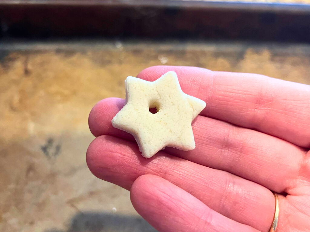 Woman holding a star salt dough ornament with a hole punched in it.