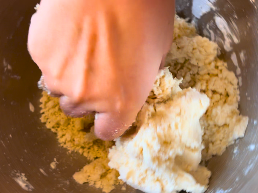 Woman squishing shortbread cookie dough together.