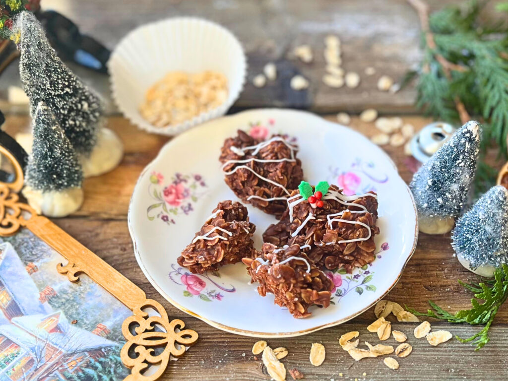 A white and pink floral plate with four chocolate haystacks on it. They are all decorated with a white icing drizzle and one has a festive holly decoration.
