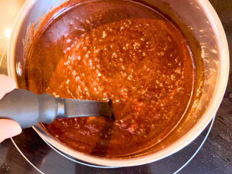 A sauce pot simmering with a chocolate mixture in it.