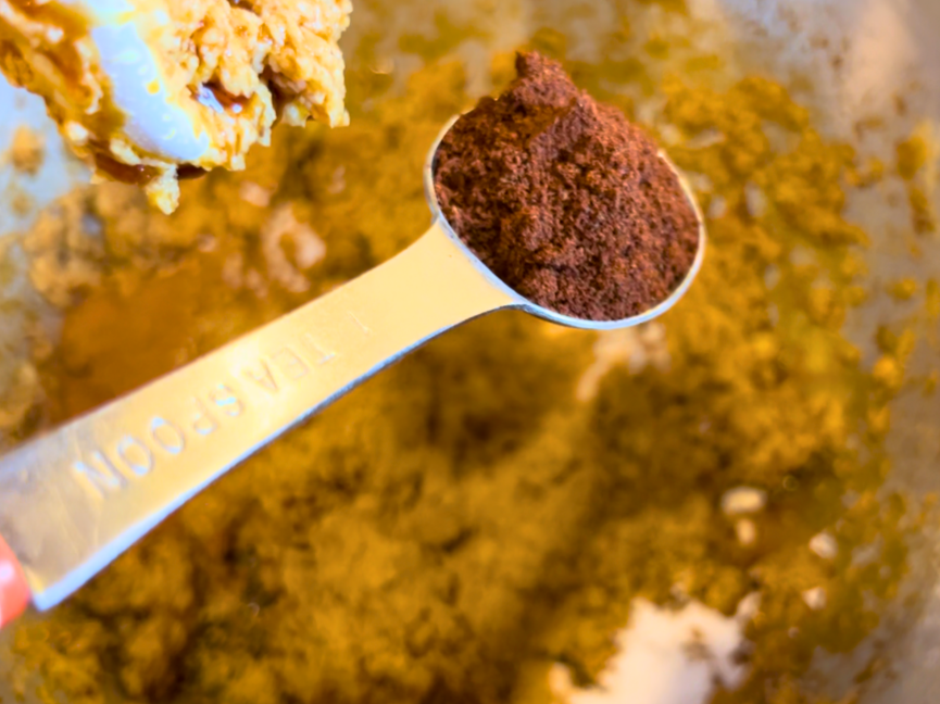 Woman adding ground cloves to gingerbread batter