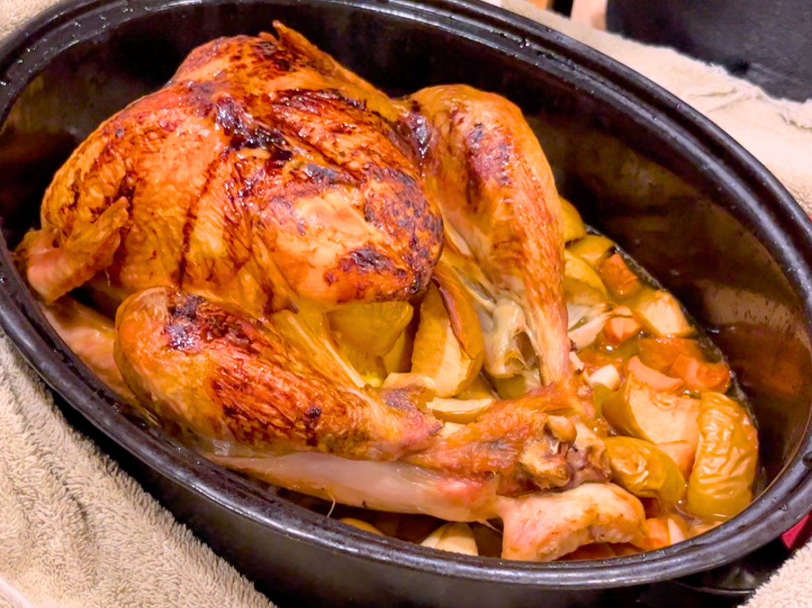 A cooked turkey in a black roasting pan.