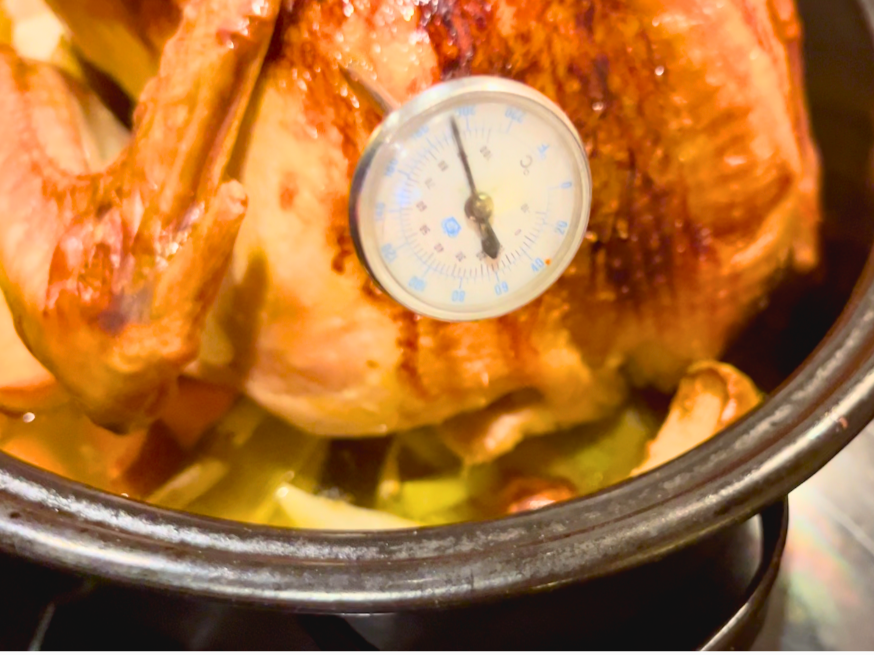 A cooked turkey with a meat thermometer in it.