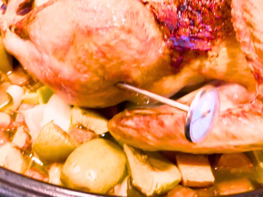 A cooked turkey with a meat thermometer in the thigh