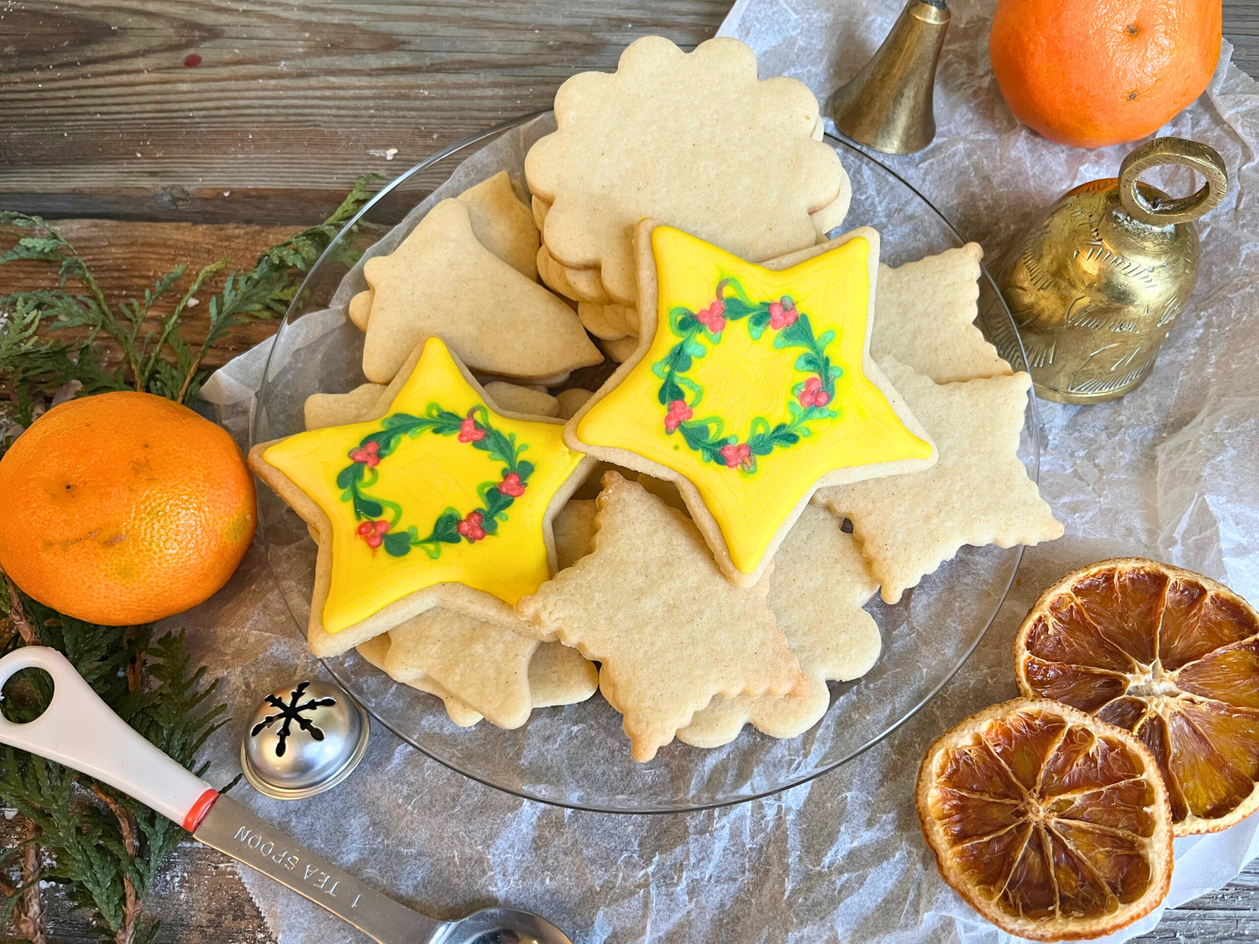A plate of sugar cookies. Two of the cookies are decorated stars with wreaths in the middle.