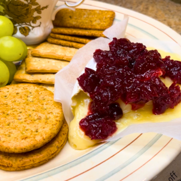 Baked brie with cranberry sauce. Crackers and grapes on the tray as well.