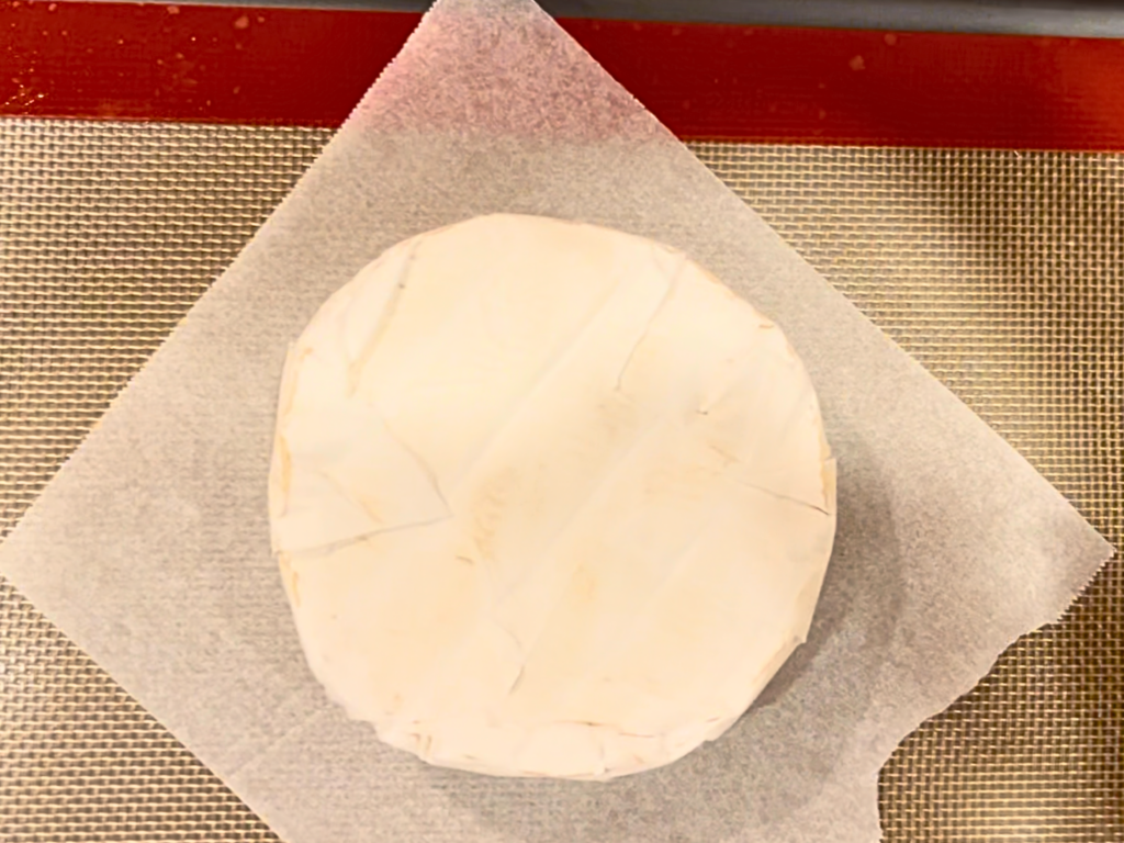 A wheel of brie on a piece of parchment paper.
