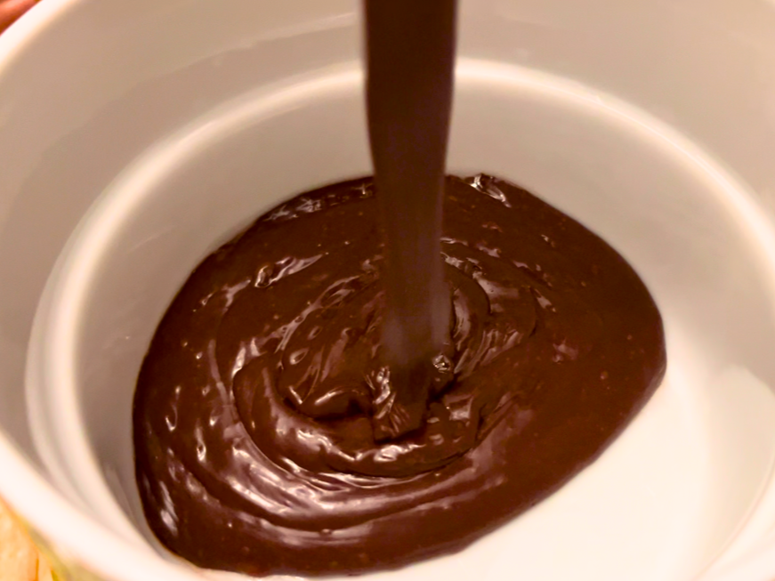 Woman pouring chocolate fondue into a fondue pot.