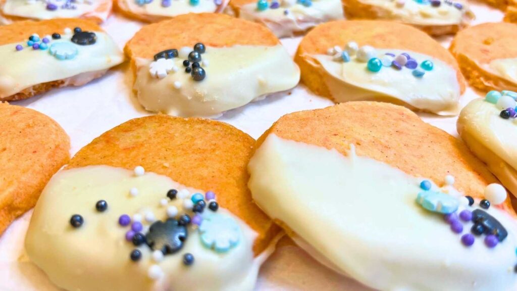 A close up look at orange and cardamom cookies decorated with white chocolate and sprinkles.