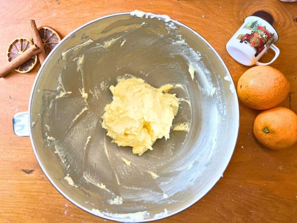 A metal bowl with creamed butter and sugar inside.