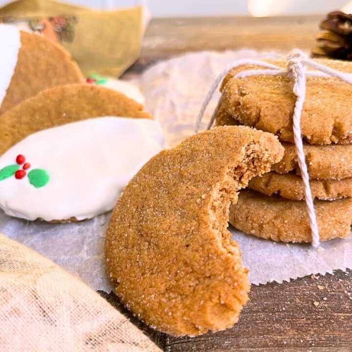 A stack of gingerbread cookies tied with kitchen twine. There are more cookies in the back decorated with icing and sprinkles.