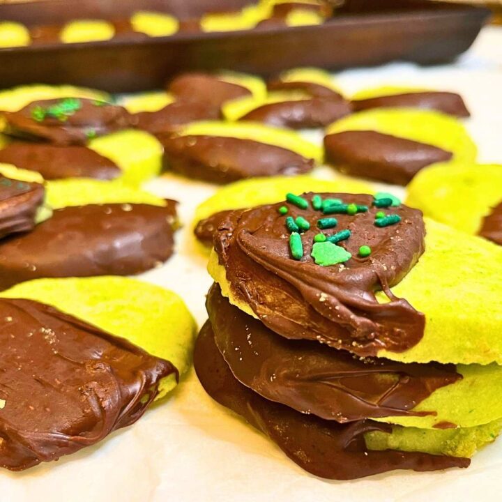 Some mint shortbread cookies that have been dipped in chocolate. Some have sprinkles.