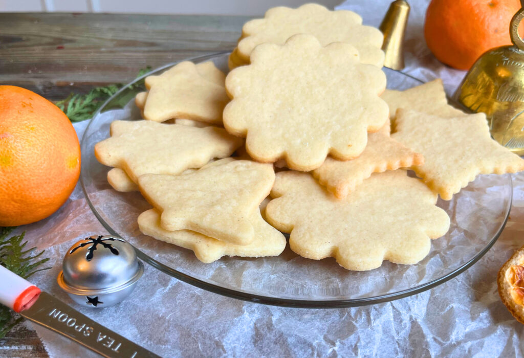 A glass plate with cut-out sugar cookies on it. 