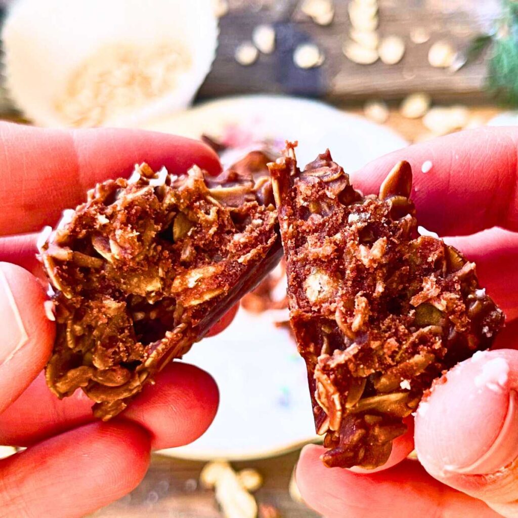 A woman is splitting a chocolate haystack cookie to show the inside.