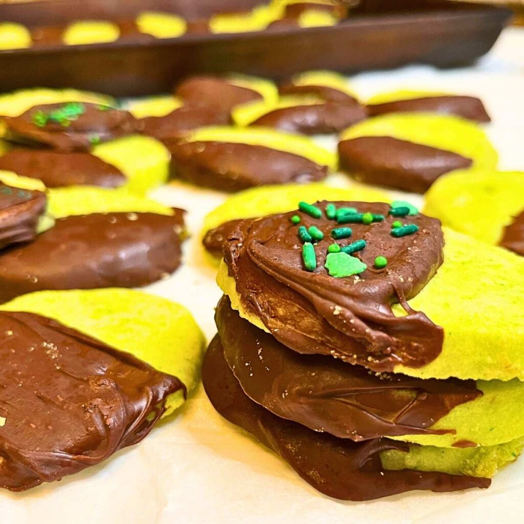 Some mint shortbread cookies on a piece of parchment paper. Some are stacked.