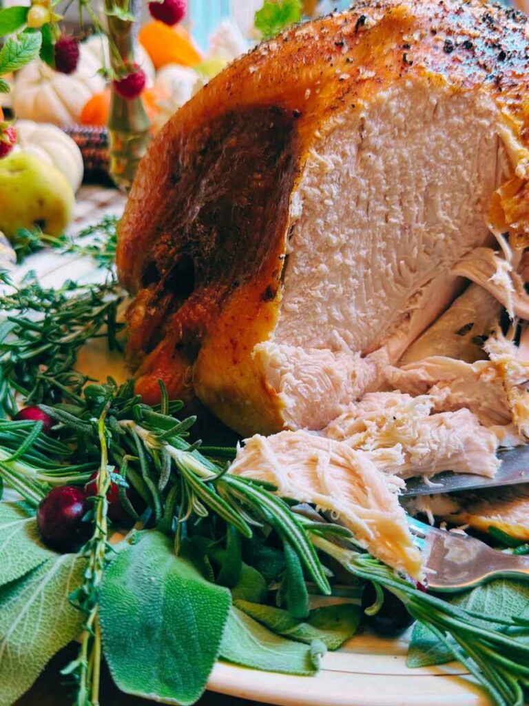 A partially sliced turkey on a platter decorated with fresh herbs.