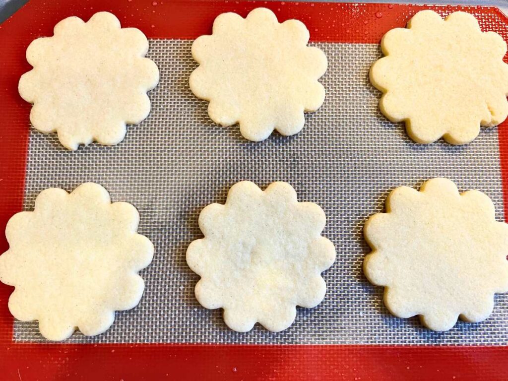 Cut out sugar cookies on a lined baking sheet.