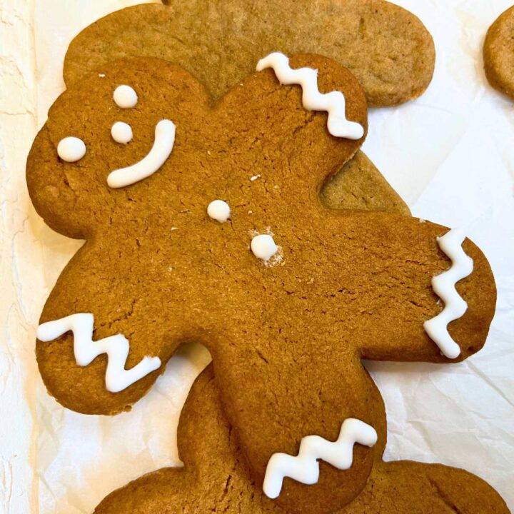 A decorated gingerbread man. There are more undecorated cutouts in the background.