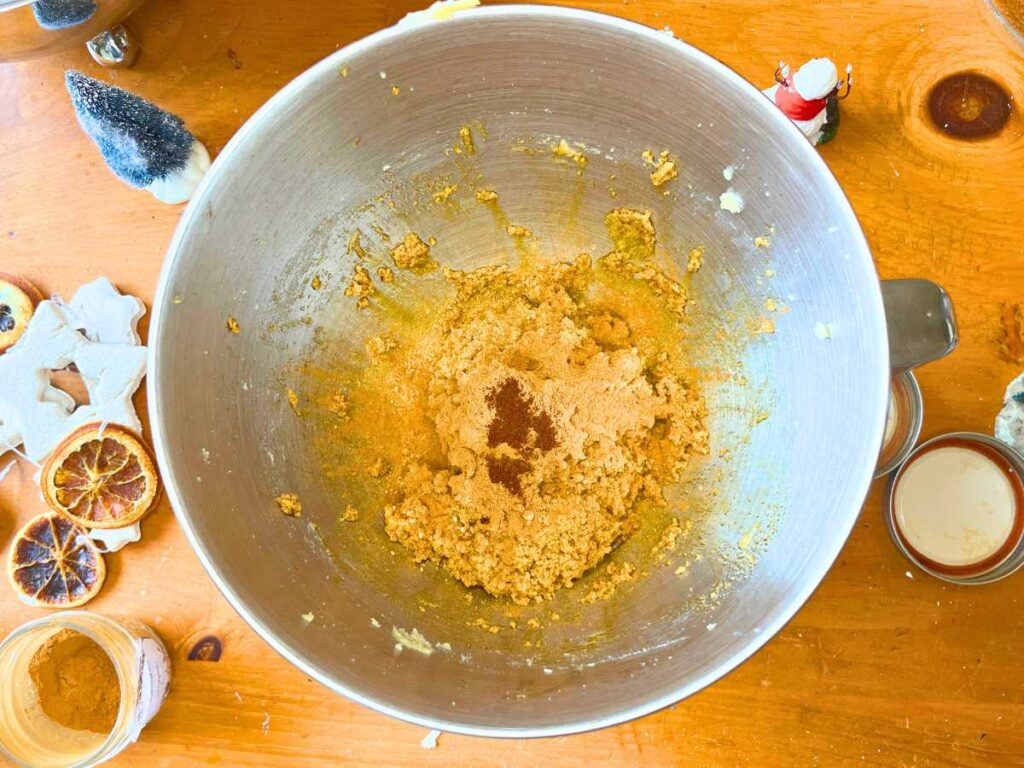 A metal bowl with gingerbread spices on top of batter.