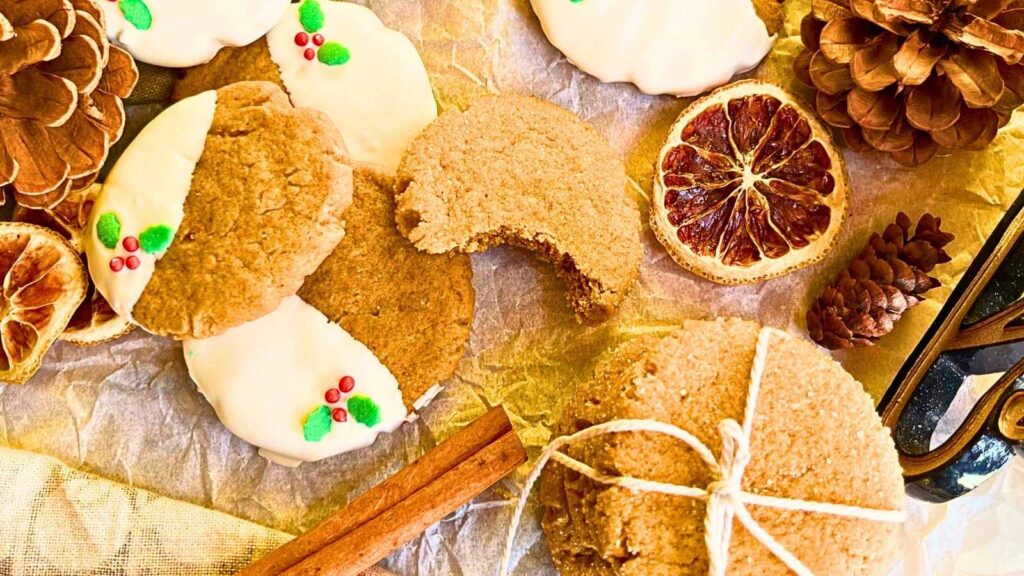 Some gingerbread cookies on a table. Some are dipped in white chocolate and decorated with festive sprinkles.