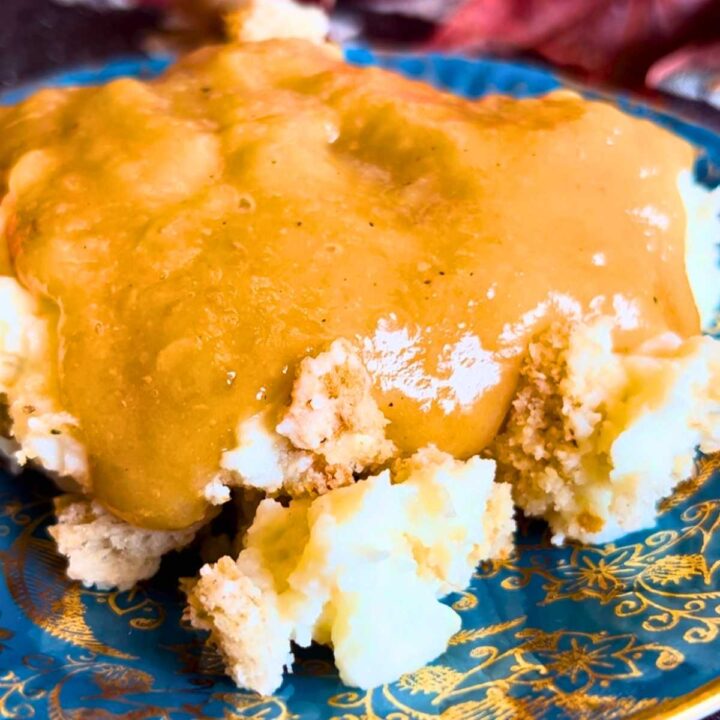 A plate of mashed potatoes with gravy on top.