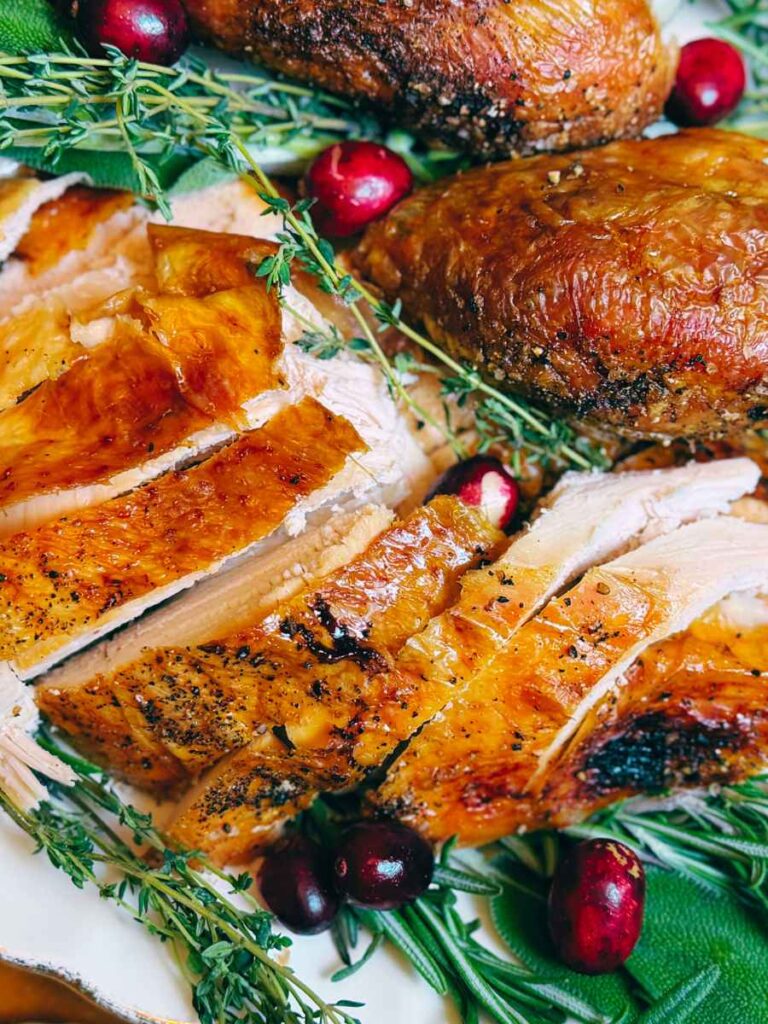 A sliced turkey on a platter of fresh herbs.
