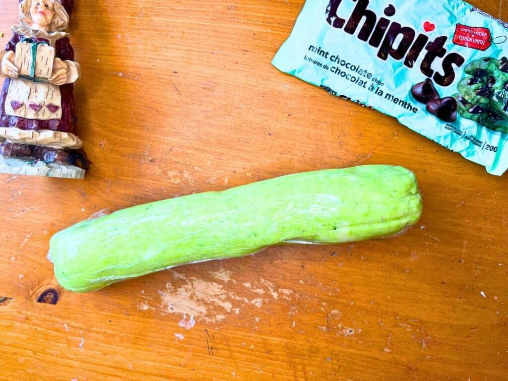 A log of mint chocolate shortbread dough wrapped in plastic wrap.