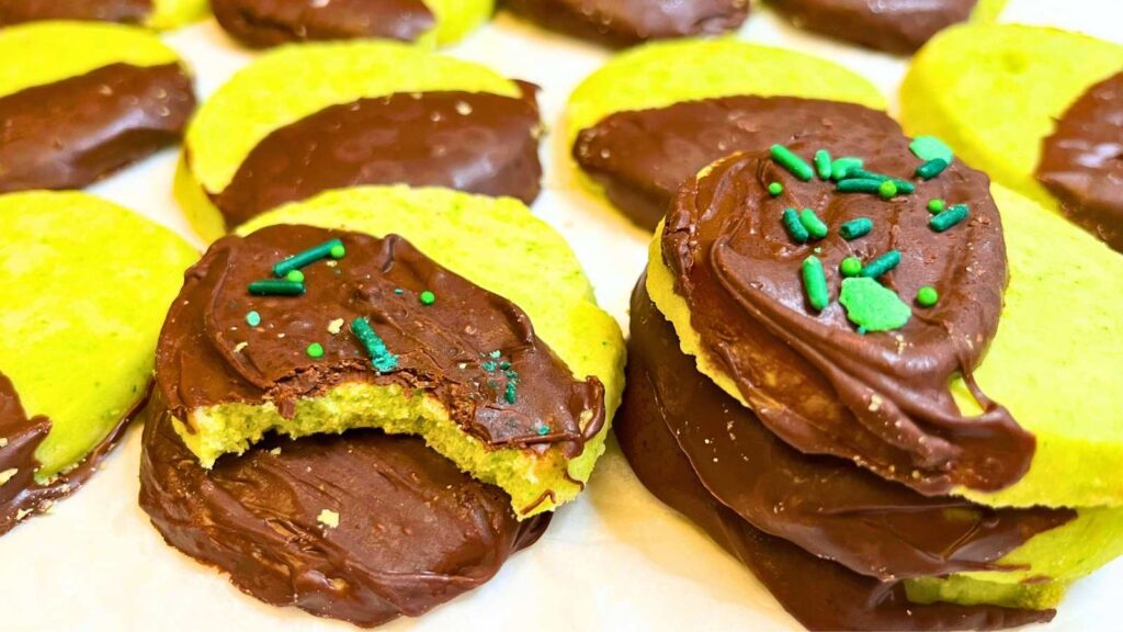 A batch of mint chocolate dipped shortbread cookies. One has a bite out of it.