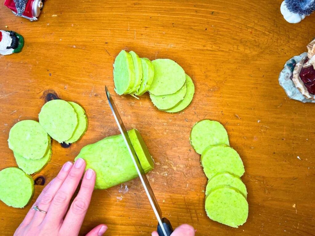 A woman is cutting mint slice-and-bake cookies.