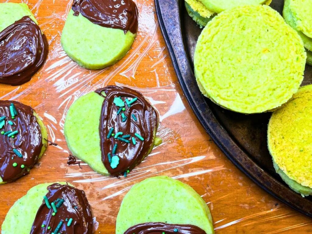 Some mint shortbread cookies have been dipped in chocolate. There are more cookies off to the side.