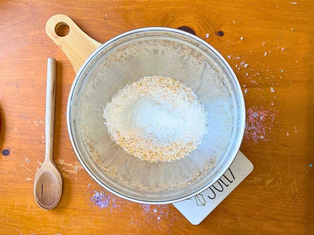 A large metal bowl with oats and coconut inside.