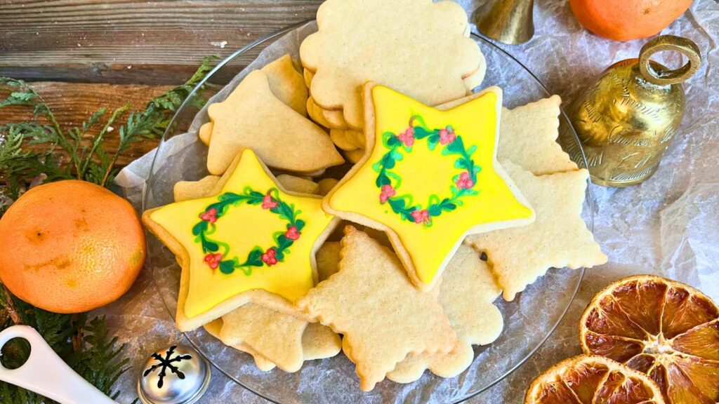 Sugar cookies on a glass plate. There are two decorated stars on top.